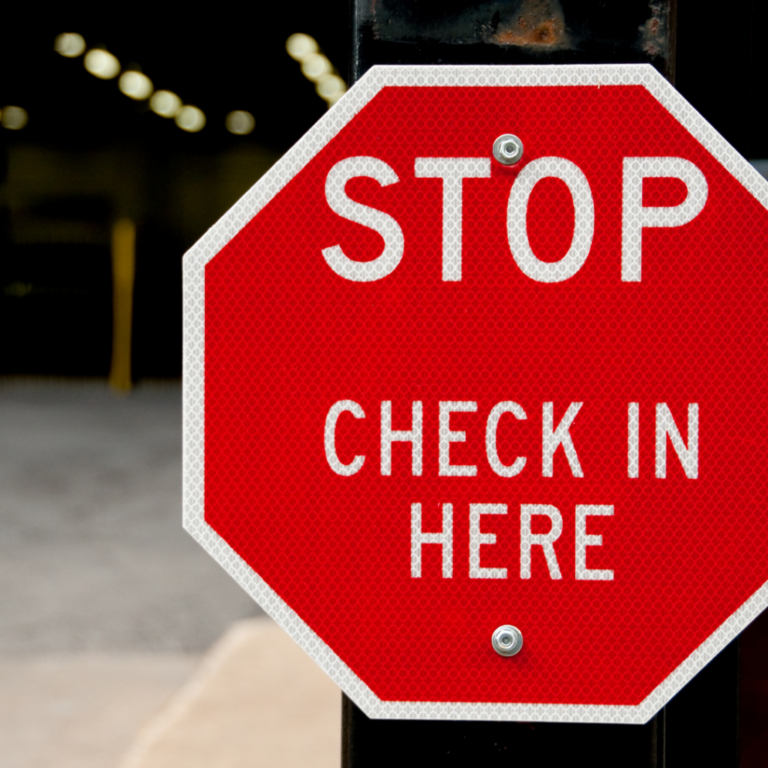 red stop sign that reads Check in Here