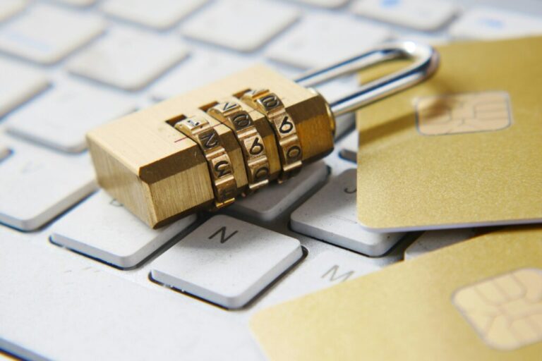 a combination lock sits atop a keyboard, along with two gold cards with microchips visible